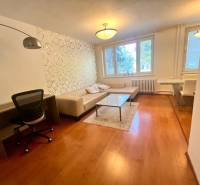 Nappali egy háromszobás lakásban kanapéval, asztallal és íróasztallal.