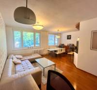 Nappali egy háromszobás lakásban kanapéval, asztallal és étkező sarokkal.