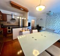 Konyha és nappali egy 3 szobás lakásban modern bútorokkal és dekoratív fallal.