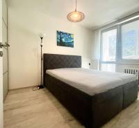 Hálószoba franciaággyal, festménnyel és állólámpával egy háromszobás lakásban.