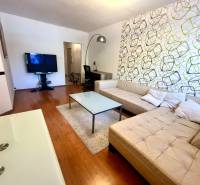 Nappali bézs kanapéval és televízióval egy háromszobás lakásban.