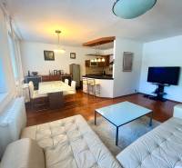 Nappali konyhával egy háromszobás lakásban, felszerelés tartalmazza a kanapét, az asztalt és a televíziót.