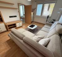 Nappali egy háromszobás lakásban kanapéval és fa dekorációjú padlóval.