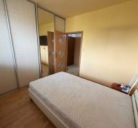 Hálószoba egy háromszobás lakásban ággyal, gardróbszekrényekkel és fa dekorációjú padlóval.