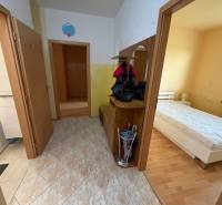 Folyosó egy háromszobás lakásban, járólappal, fürdőszobába és hálószobába nyíló bejárattal, fa dekor padlóval.