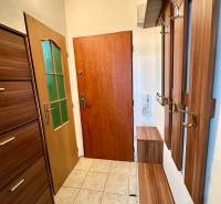 Garzonlakás előszobával, fa ajtókeretekkel és csempével, elegáns dizájn és praktikus tárolóhelyek.