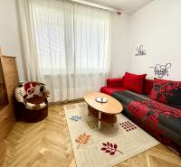 Garzonlakás fa dekor padlóval, piros kanapéval és fotellel.