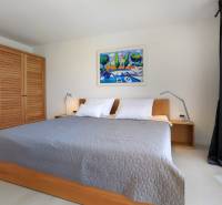 Hálószoba a villában nagy ággyal, fa szekrénnyel és képpel a falon.