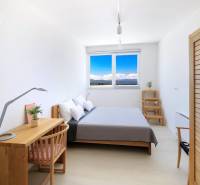 Világos hálószoba a villában egyszerű bútorokkal és kilátással a tájra.