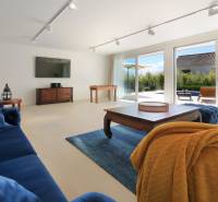 Nappali egy villában sötétkék bútorokkal, TV-vel és nagy ablakokkal.