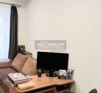 Nappali kanapéval, asztallal és fa dekorációjú padlóval egy háromszobás lakásban.