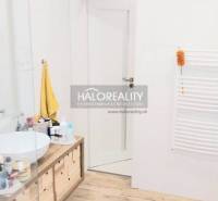 Fürdőszoba fa dekor padlóval, pultos mosdóval és fehér falakkal egy háromszobás lakásban.