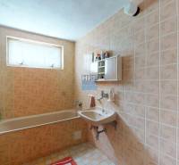 Fürdőszoba családi házban régebbi csempével, káddal és mosdóval.