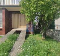 Családi ház a Radošovce-i Vieska utcában, gyep és fa a bejárat előtt.