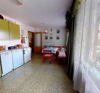 Családi ház konyhája retro bútorokkal, asztallal, nagy ablakkal és dekorációkkal.