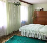 Hálószoba családi házban szőnyegekkel, függönyökkel és fa szekrénnyel.