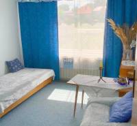 Szoba egy családi házban kék függönyökkel, kanapéval és ággyal.