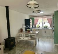 Családi ház belső tere konyhával, étkezőasztallal és cserépkályhával.