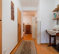 Előszoba egy háromszobás lakásban csempével, fa polccal és dekoratív tárgyakkal.