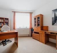 Dolgozószoba könyvtárral egy háromszobás lakásban, fa dekorációval a bútorokon.