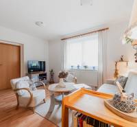 Nappali egy háromszobás lakásban kényelmes bútorokkal és fa mintázatú padlóval.