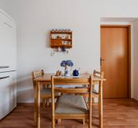 Étkezőasztal székekkel, hűtőszekrény és fa mintázatú padló a háromszobás lakásban.