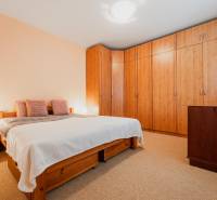 Hálószoba egy háromszobás lakásban ággyal, beépített szekrénnyel és fa dekorációjú padlóval.