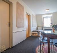 Szálloda és panzió belső tere kerek asztallal, szőnyeggel, TV-vel és díszített falakkal.