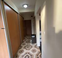 Keskeny folyosó egy egyszobás lakásban, jellegzetes csempével és tolóajtós szekrényekkel.