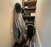 Tárolóhely ruházattal, sapkákkal, cipőkkel és porszívóval egy garzonlakásban.