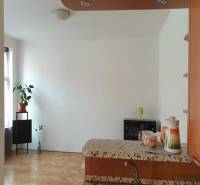 Egy 2 szobás lakás belső tere fa mintázatú padlóval és egyszerű dekorációval.