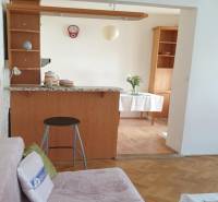 Nappali kanapéval, bárpulttal és fa dekorációjú padlóval egy kétszobás lakásban.