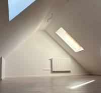 Tetőtéri szoba fa dekoros padlóval és tetőablakokkal egy háromszobás lakásban.