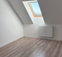 Tetőtéri szoba fa dekorációs padlóval és tetőablakkal egy háromszobás lakásban.