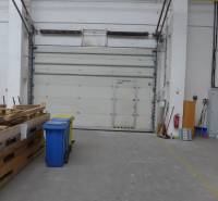 Raktárak és csarnokok raklapokkal, konténerekkel és nagy ajtókkal.