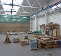 A raktárban raklapok vannak építőanyaggal és polcok táblákkal.