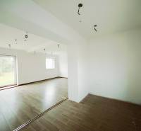 Családi ház belső tere fa dekorációjú padlóval és nagy ablakokkal a kertre.