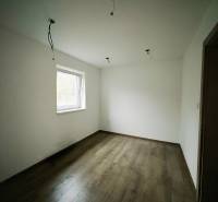 Szoba egy családi házban fehér falakkal és fa dekorációjú padlóval.