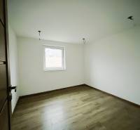 Szoba egy családi házban fehér falakkal és fa mintázatú padlóval.