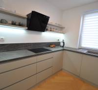 Konyha egy családi házban sötét munkalappal és fa dekorációjú padlóval.