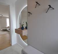 Családi ház belső tere fa mintázatú padlóval, tükörrel és szobanövényekkel.