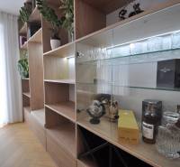 Családi ház belső tere szekrénnyel, üvegpolcokkal és fa dekoros padlóval.