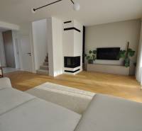 Nappali egy családi házban kandallóval és fa mintázatú padlóval.