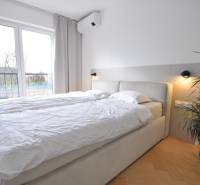 Hálószoba családi házban ággyal, növénnyel és fa dekorációjú padlóval.