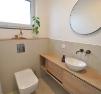 Fürdőszoba családi házban kerek tükörrel, mosdóval és fa dekorációjú padlóval.