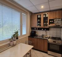 Konyha egy háromszobás lakásban gáztűzhellyel, szekrényekkel és étkezőasztallal.