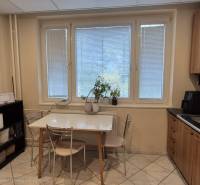 A háromszobás lakás konyhája étkezőasztallal, konyhapulttal és mikrohullámú sütővel.