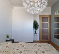 Hálószoba dekoratív lámpával, gardróbszekrénnyel és fa mintázatú padlóval egy háromszobás lakásban.