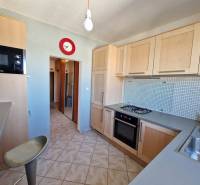 Konyha egy háromszobás lakásban gáztűzhellyel, világos szekrényekkel és csempével.