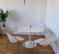 Étkező sarok egy háromszobás lakásban, fa dekorációjú padlóval és díszes székekkel.